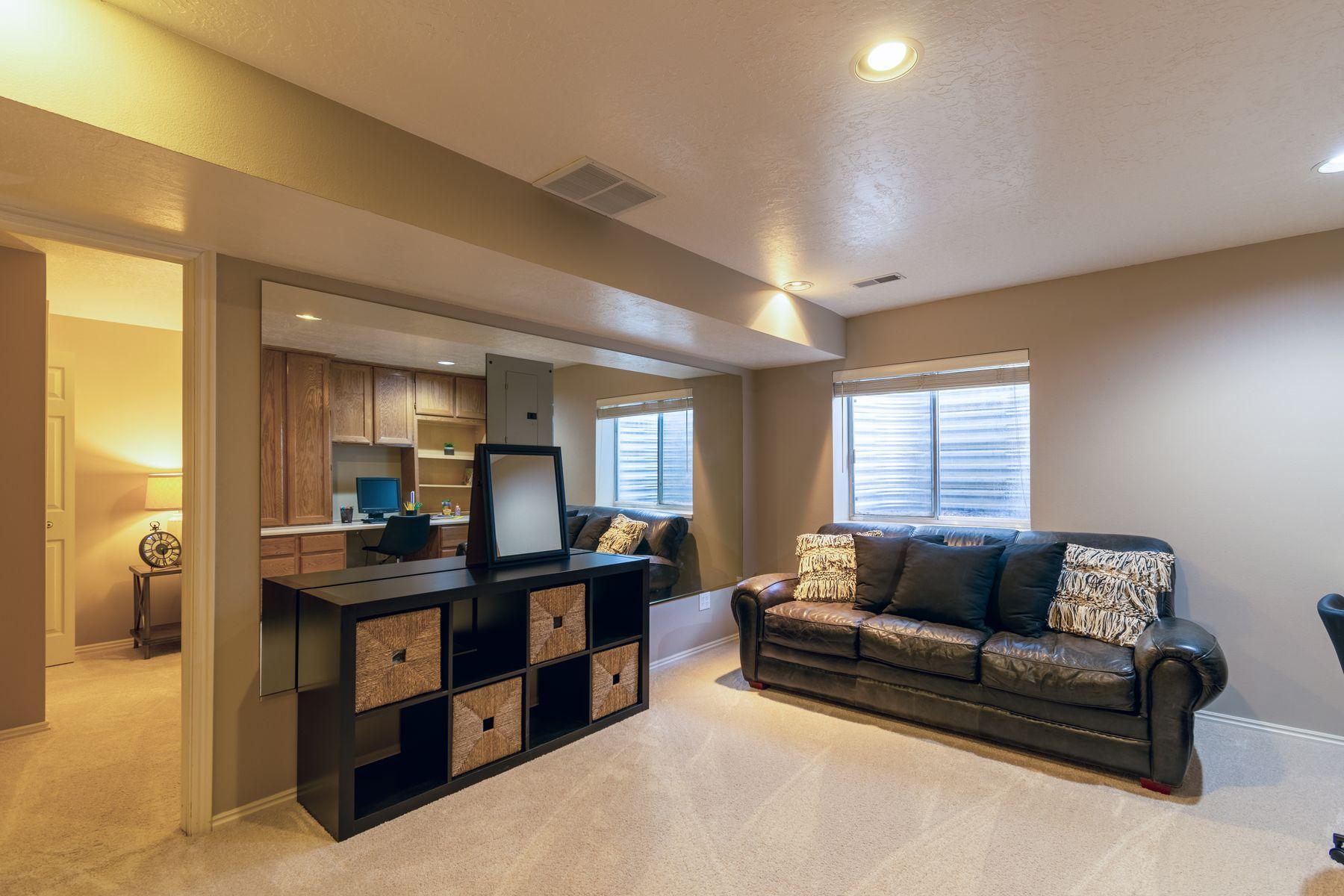 Finished basement living room with a leather sofa, built-in storage, and daylight windows