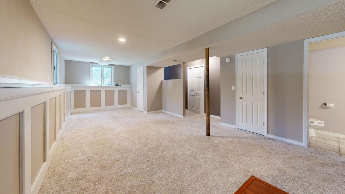 Finished basement family room with recessed lighting and neutral carpet