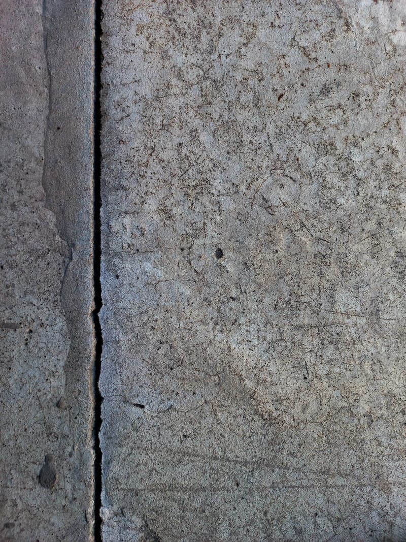 Vertical crack running through a gray concrete wall